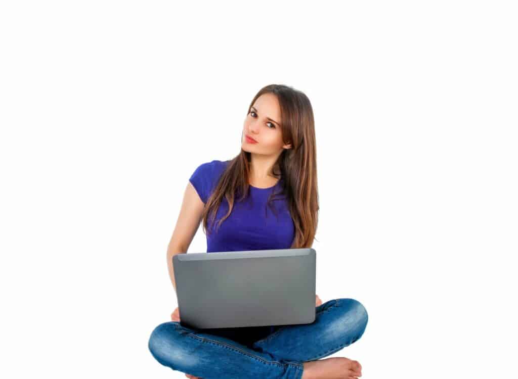 Das Foto zeigt eine junge, sitzende Frau im Schneidersitz mit einem Laptop vor einem weißen Hintergrund.