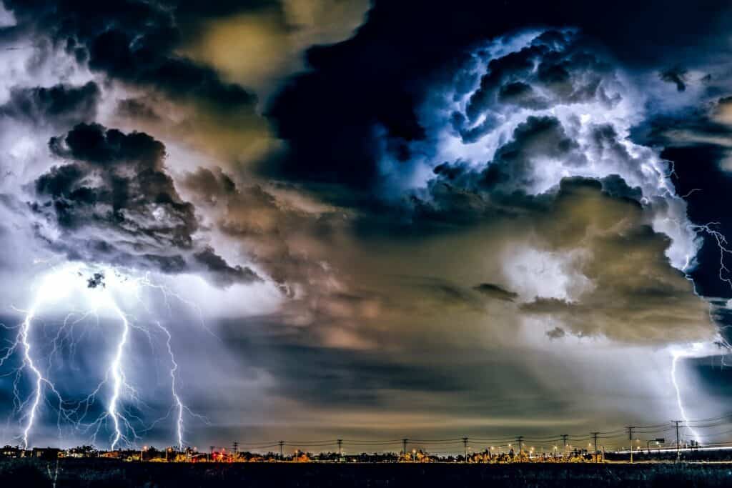 Auf dem Bild sind schwarze Gewitterwolken zu sehen und ein Blitz der aus dem Himmel schießt. Unwetter als außergewöhnlicher Umstand.