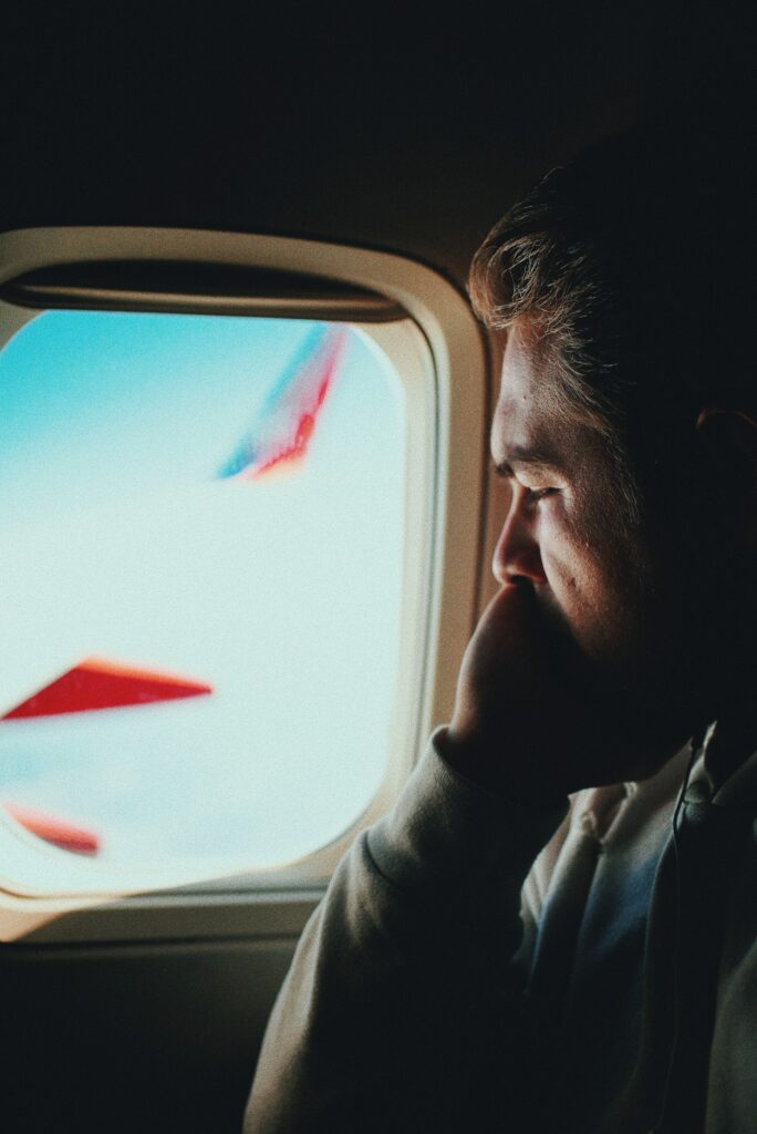 Man sieht einen ängstlichen Mann in einem Flugzeug. Er schaut aus dem Fenster.