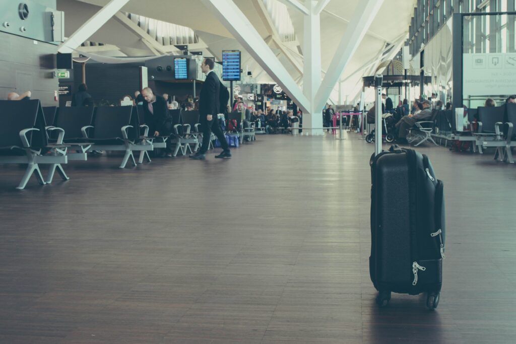 Es ist ein Flughafenterminal mit Menschen und Koffern zu sehen.
