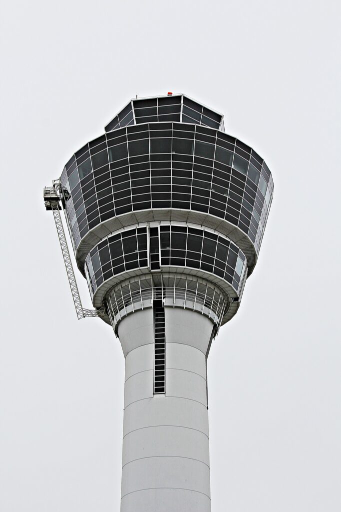 Man sieht einen Flughafentower vor grauem Himmel.