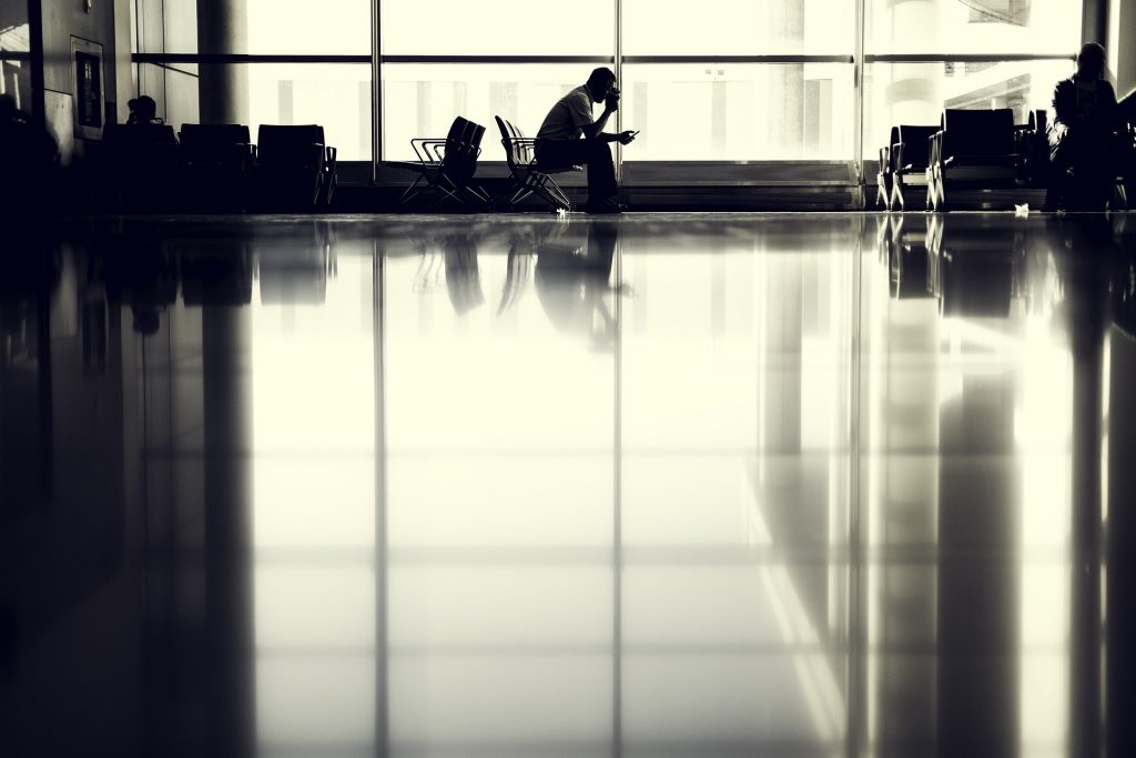 Man sieht ein Flughafenterminal mit einer wartenen Person in Schwarz-Weiß.