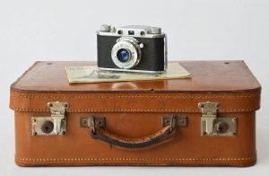 Großer alter Koffer, drauf auf dem Koffer sind eine Papierchen und eine Retro-Kamera