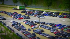 Man sieht die Luftaufnahme eines Parkplatzes mit Autos in Miniaturform.