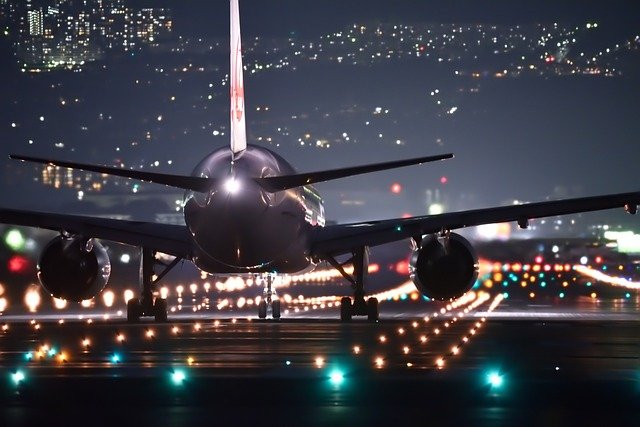Es ist ein Flugzeug bei Nacht auf einer Landebahn zu sehen.