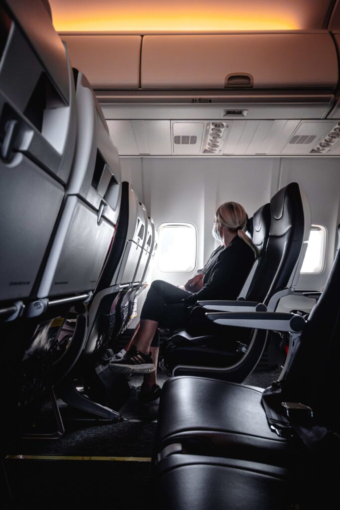 Frau sitzt im Flugzeug und schaut aus dem Fenster. 