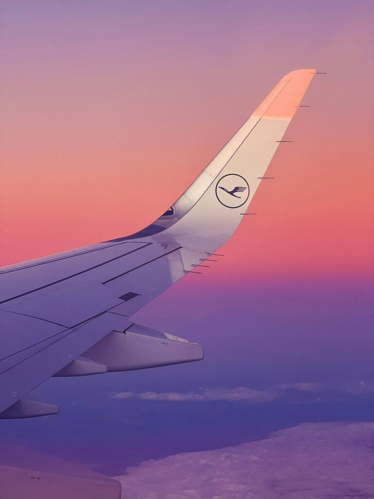 Lufthansa Flugzeugflügel vor lila Himmel