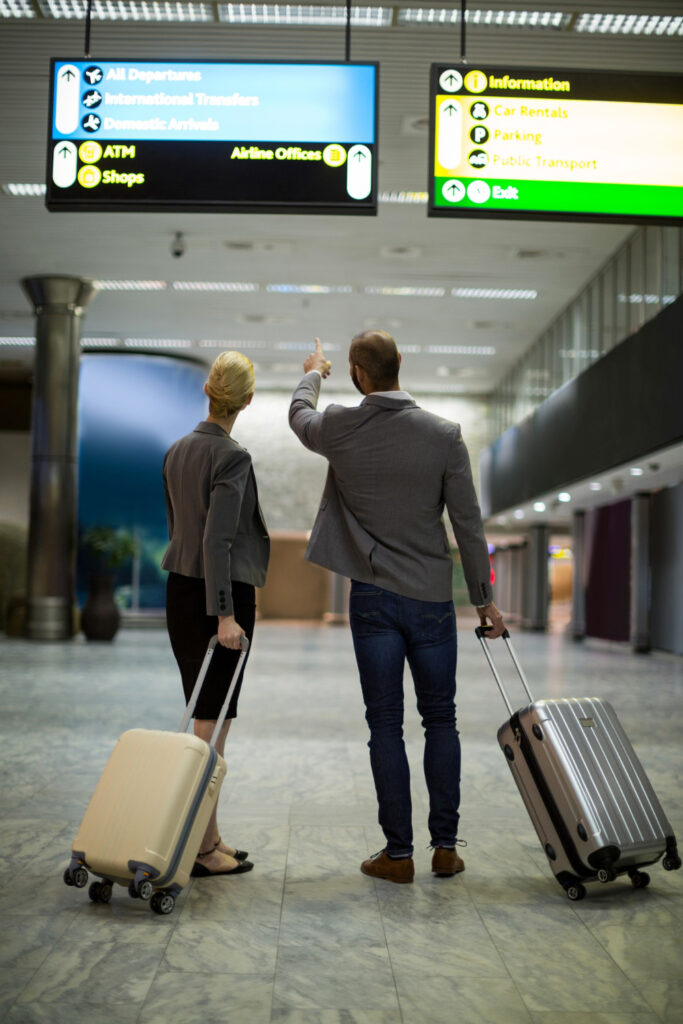 Geschäftsmann und -frau schauen auf Anzeigetafel im Flughafen.