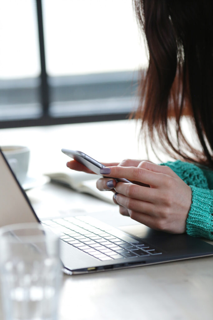 Eine Frau bucht einen Flug, Smartphone und Laptop. 