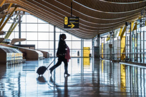 Frau läuft mit Koffer durch einen Terminal.