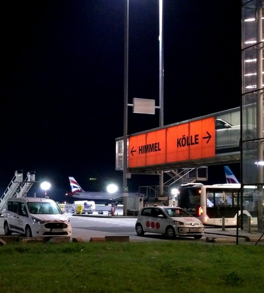 Fluggastbrücke mit dem Text "Himmel Kölle" bei Nacht am Flughafen Köln/Bonn