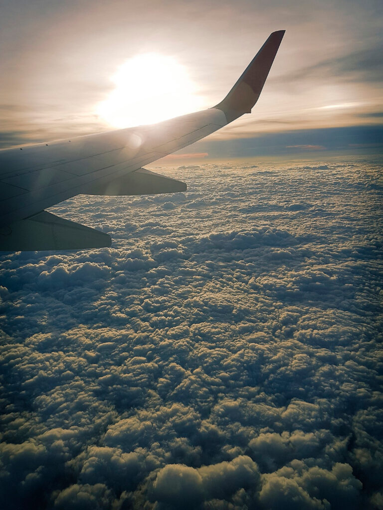 Blick aus Flugzeug auf dichte Wolken und Sonne. 