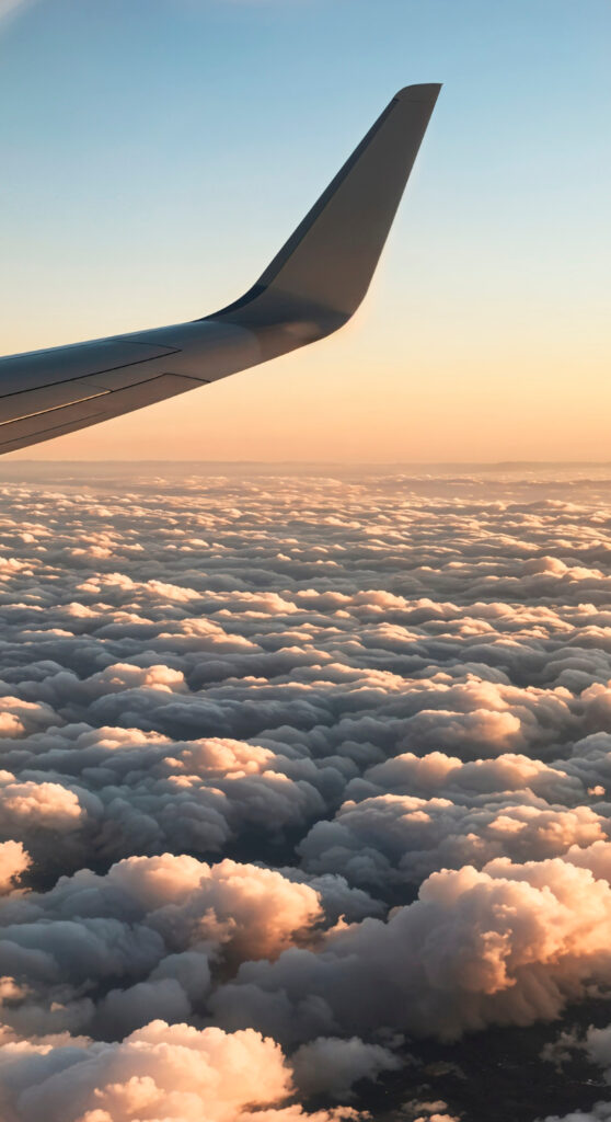 Sicht aus Flugzeug auf Flüger über Wolken mit Sonnenaufgang.