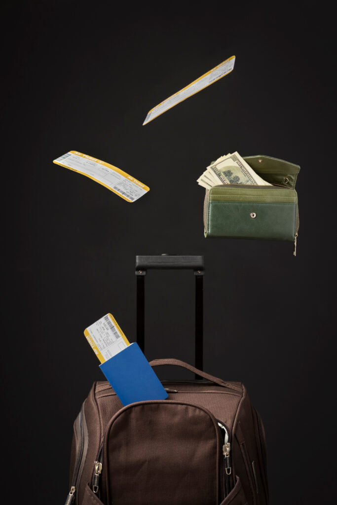 Reisetasche mit Geldbörse und Flugtickets vor schwarzem Hintergrund. 
