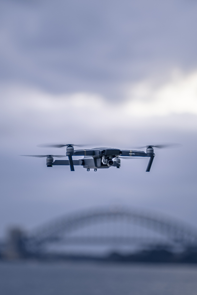 Fliegende Drohne mit Brücke im Hintergrund.