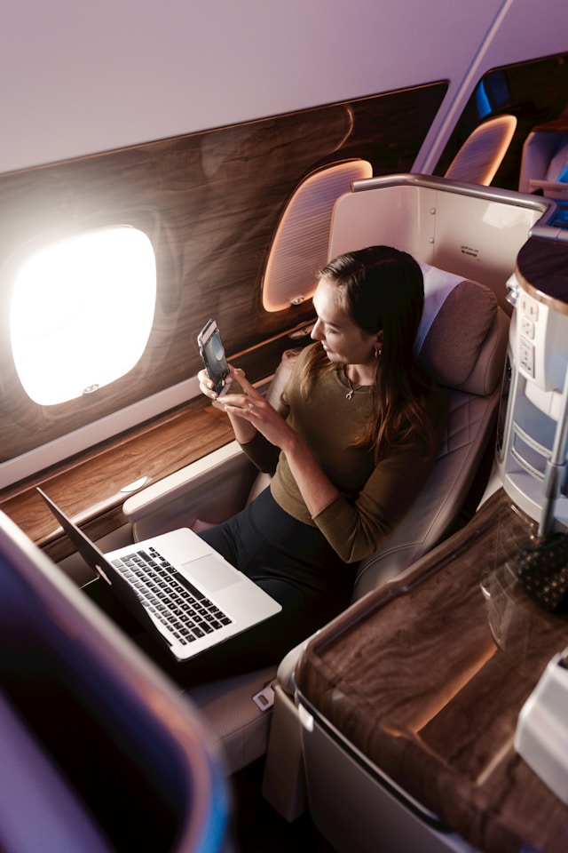 Frau sitzt zufrieden in der Business Class im Flugzeug. 