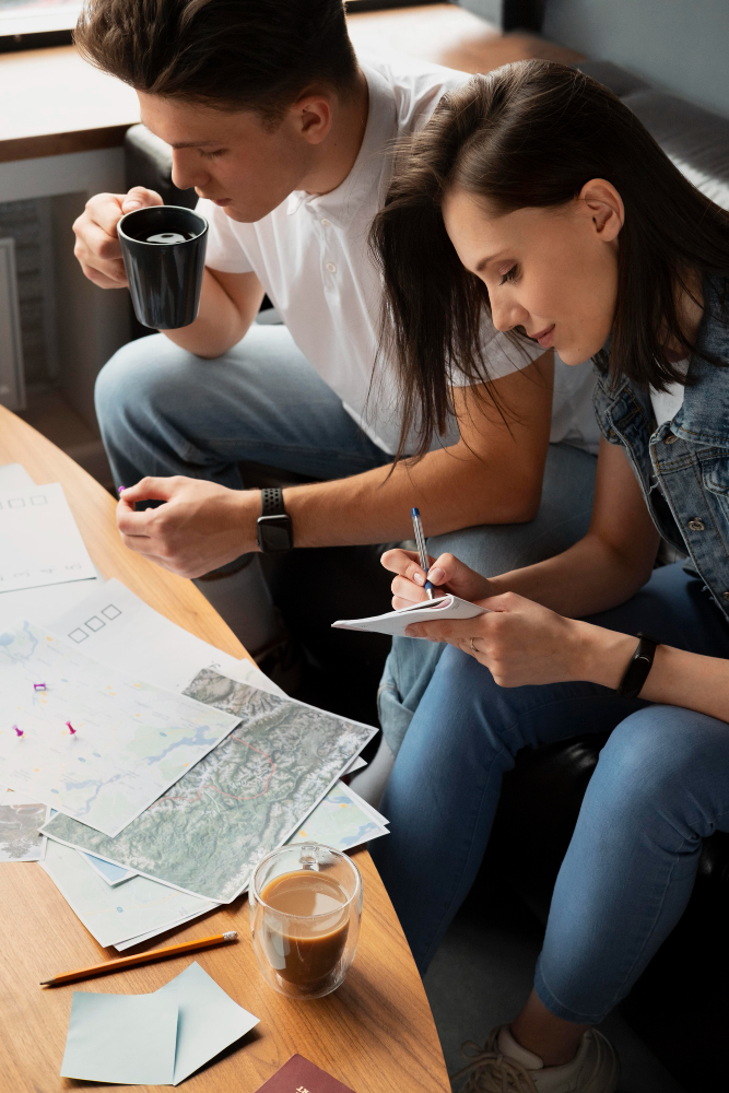Frau und Mann sitzen am Tisch und planen eine Reise mit Weltkarten.