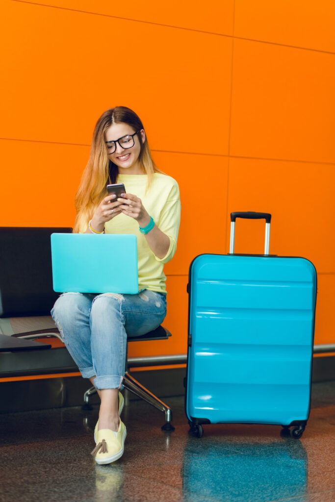 Eine Frau vor orangem Hintergrund am Flughafen recherchiert Passengers friend.