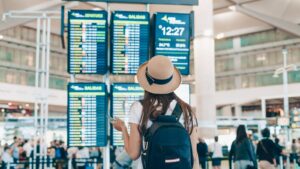 Reisende mit Rucksack schaut am Flughafen auf die Abflugtafel